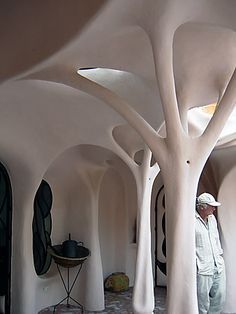 a man standing in the middle of a room with white walls and arches on both sides