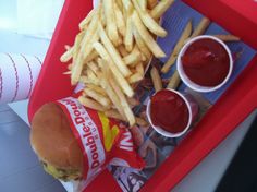 a tray with french fries, ketchup and a burger on it sitting on a table