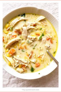 a white bowl filled with chicken and corn soup on top of a cloth covered table