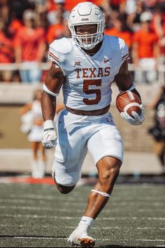 a football player running with the ball in his hand and people watching from the stands