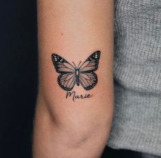 a woman's arm with a butterfly tattoo on it that says marie in black ink