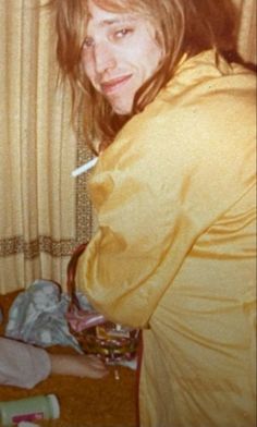 a woman with long hair sitting on a bed next to a baby in a crib