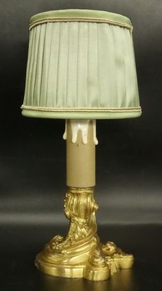 a gold lamp with a green shade on it's base and an elephant figurine underneath