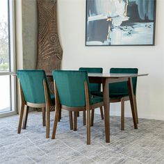 a dining room table with green chairs and a painting on the wall