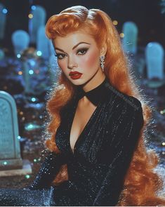 a woman with long red hair in a black dress posing for a photo next to a gravestone