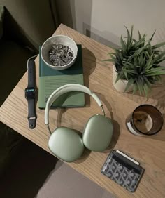 a table with headphones, a book and a cell phone on it next to a potted plant