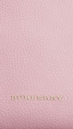 the word burberry is written in gold on a pink leather textured surface