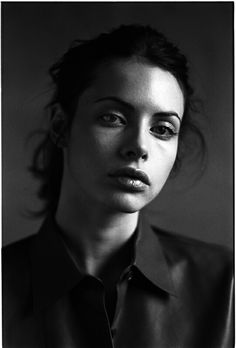 a black and white photo of a woman wearing a shirt with her hair pulled back