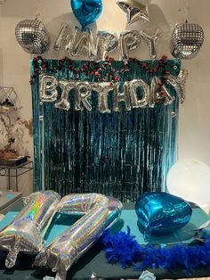 a birthday party with balloons, streamers and blue decorations on a table in front of a backdrop that says happy birthday