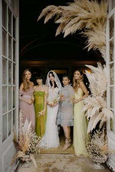 a group of women standing next to each other in front of an open door with feathers