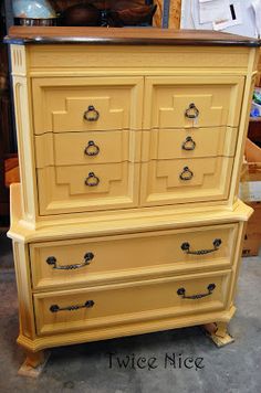 an old dresser is painted yellow and has black hardware on the bottom drawer, which matches the rest of the furniture