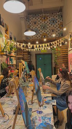 people sitting at tables with easels and paintings on them