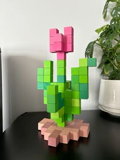 a plant made out of blocks sitting on top of a table next to a potted plant