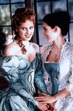 two women in dresses are smiling at each other