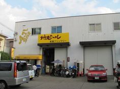 an outside view of a motorcycle repair shop with cars and motorcycles parked in the lot