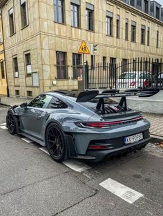 a grey sports car parked in front of a building on the side of a street