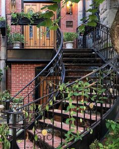 an iron stair case in front of a brick building with potted plants on it