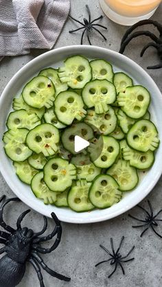 a white bowl filled with cucumbers on top of a table next to halloween decorations