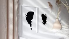 two black silhouettes are on the wall next to a vase