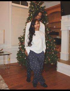 two people standing in front of a christmas tree