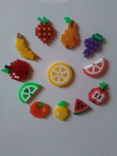 a group of fruit and vegetable brooches arranged in a circle on a white surface