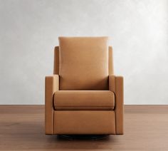 a brown leather chair sitting on top of a wooden floor next to a white wall