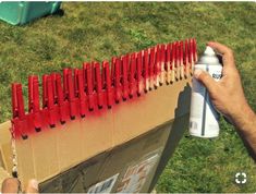 a person is spray painting the outside of a cardboard box with red paint on it