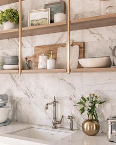 a kitchen with marble counter tops and open shelving above the sink is filled with dishes