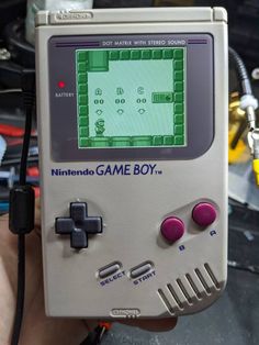 an old nintendo game boy is being held in someone's hand