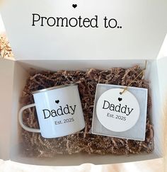 two coffee mugs in a box with the words'promote to dad'on them