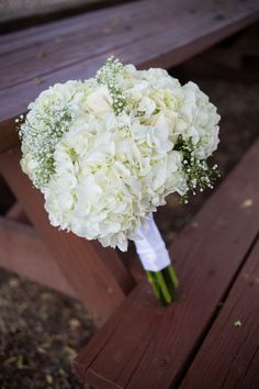 a bouquet of white flowers sitting on top of a wooden bench