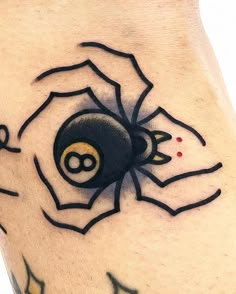 a spider tattoo on the leg with black and yellow dots in it's center