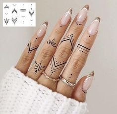 a woman's hand with tattoos on her fingers and fingernails in the shape of arrows