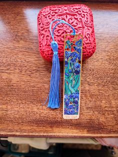 a red purse sitting on top of a wooden table next to a tassell