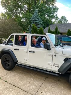 a group of people sitting in the drivers seat of a white jeep