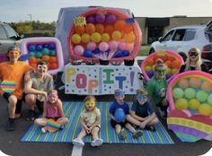 a group of people sitting on top of a parking lot next to balloons and signs