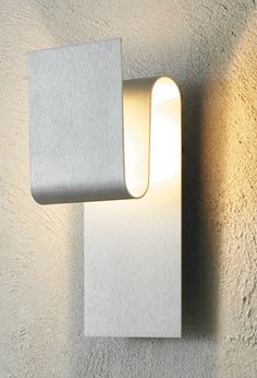 a white wall light mounted on the side of a concrete wall next to a plant