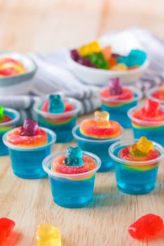 small plastic cups filled with gummy bears on top of a wooden table