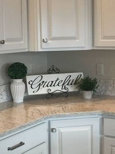 a kitchen with white cabinets and granite counter tops, including a sign that says grateful