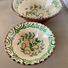 two green and white bowls sitting on top of a counter next to eachother