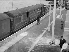 an old black and white photo of a train on the tracks with people standing next to it