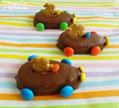 chocolate covered donuts with colorful candies in the shape of cars on a striped tablecloth