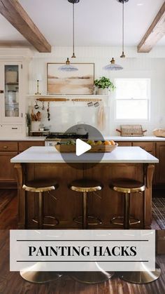 a kitchen with wooden floors and white walls, has an island in the middle that has stools on it