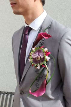 a man wearing a suit and tie with flowers on it's lapel flower