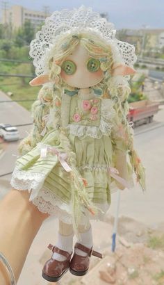 a doll is being held up in the air by someone's hand with lace on it