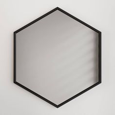 a mirror hanging on the wall in front of a white wall with black trimming