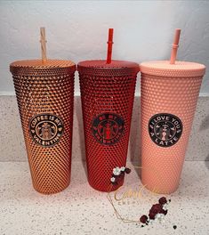 three red starbucks cups with straws in them