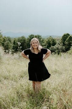 a woman standing in tall grass with her hands on her hips