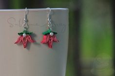 red and green flower earrings sitting on top of a white cup with silver ear wires