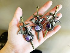 three dragon brooches sitting on top of a person's hand